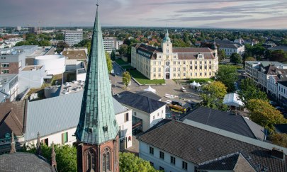 Blick auf die Stadt mit Schloss im Hintergrund und Turm der St. Lamberti-Kirche im Vordergrund. 